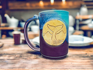 A picture of a purple and turquoise mug  with a whale tail design